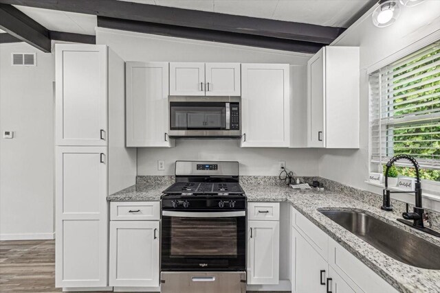 kitchen with white cabinets, stainless steel appliances, visible vents, and a sink