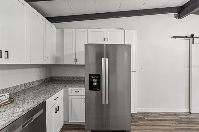 kitchen with white cabinets, dark wood-style flooring, a barn door, and stainless steel appliances