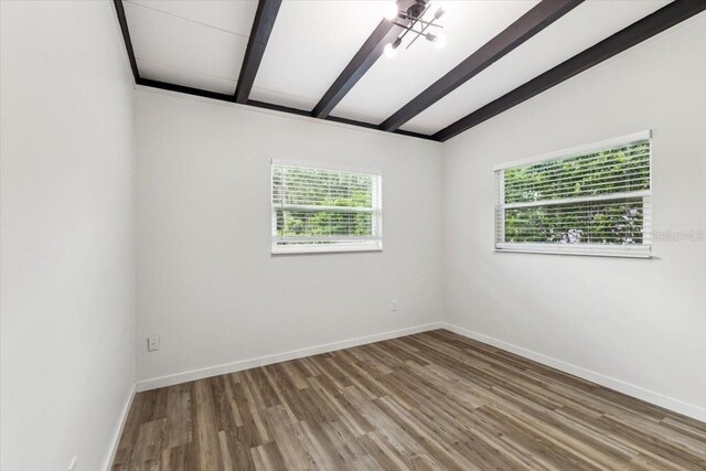 empty room featuring wood finished floors, baseboards, and lofted ceiling with beams