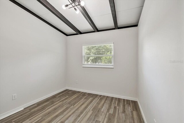 spare room featuring lofted ceiling with beams, baseboards, and wood finished floors
