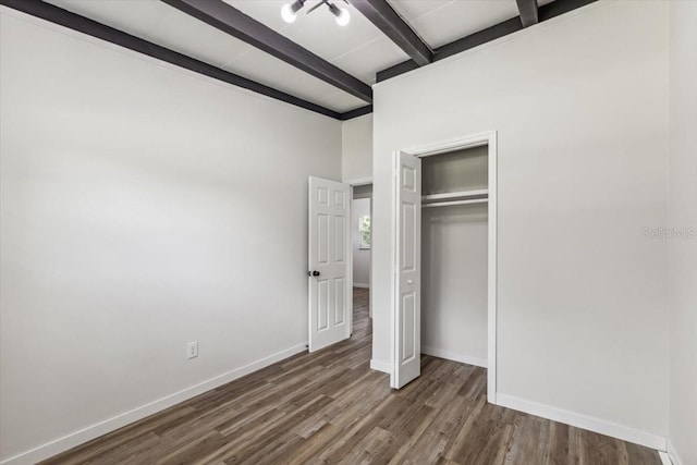 unfurnished bedroom with dark hardwood / wood-style floors, beamed ceiling, and a closet