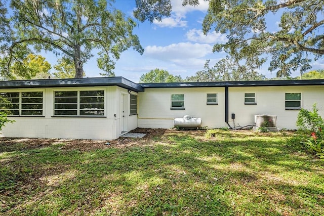 rear view of property featuring central AC and a yard