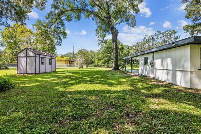 view of yard with an outbuilding, a shed, and fence