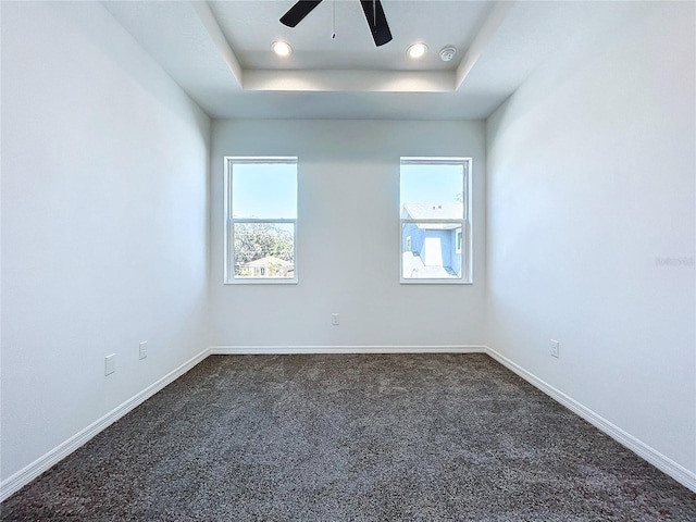 carpeted empty room featuring ceiling fan and a tray ceiling