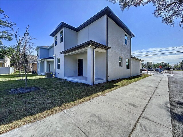 rear view of property featuring a lawn and central air condition unit