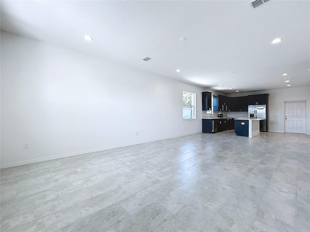 unfurnished living room with baseboards, visible vents, and recessed lighting