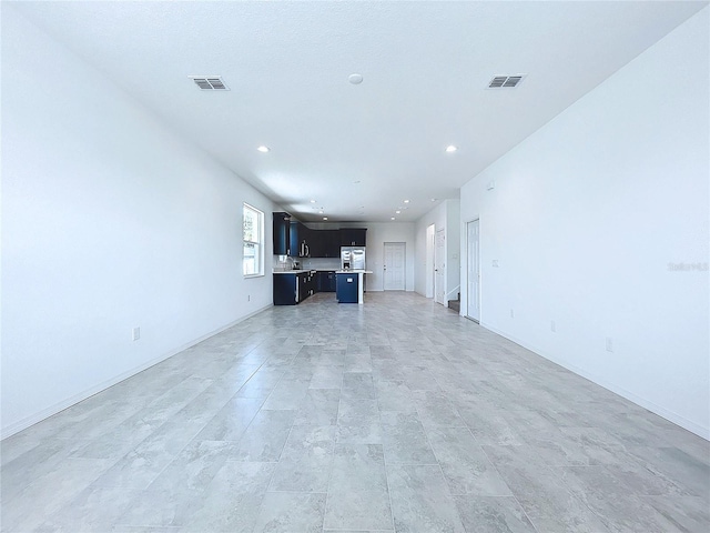 unfurnished living room with recessed lighting, visible vents, and baseboards