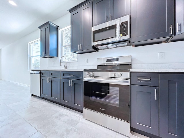 kitchen featuring baseboards, appliances with stainless steel finishes, and a sink