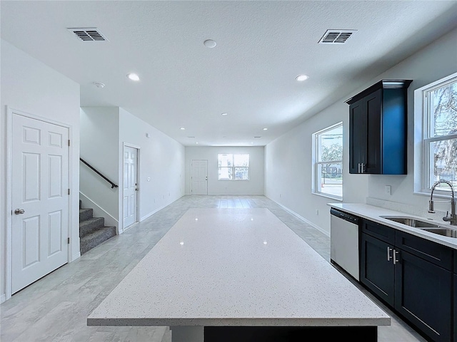 kitchen with a kitchen island, visible vents, a sink, stainless steel dishwasher, and dark cabinetry