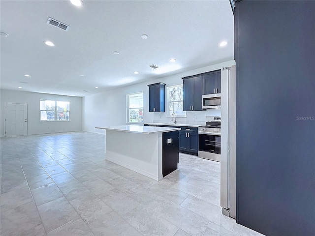 kitchen featuring a center island, stainless steel appliances, a wealth of natural light, light countertops, and open floor plan