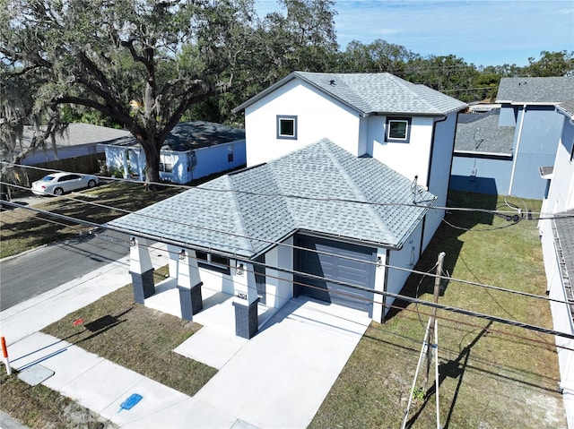 view of front of house with stucco siding, a shingled roof, concrete driveway, an attached garage, and a front lawn