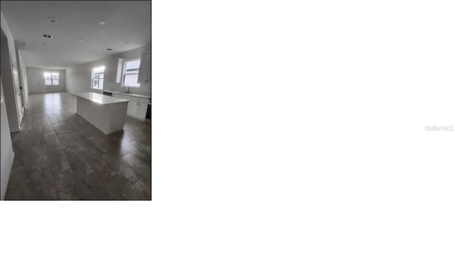 interior space featuring dark wood finished floors, open floor plan, light countertops, white cabinetry, and a sink