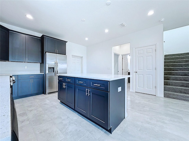 kitchen with stainless steel refrigerator with ice dispenser and a kitchen island