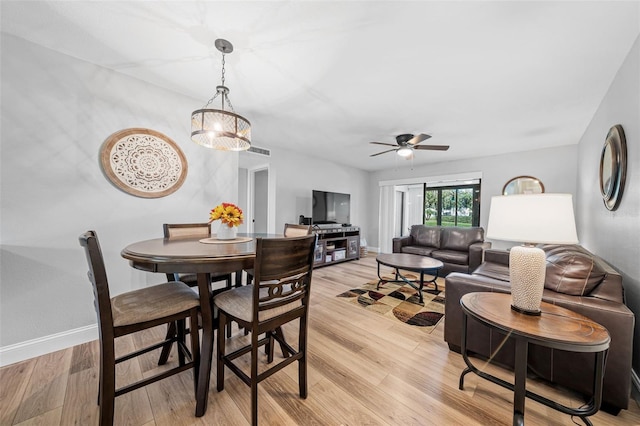 dining room featuring ceiling fan with notable chandelier and light hardwood / wood-style floors