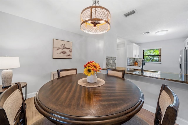 dining room with light hardwood / wood-style floors, an inviting chandelier, and sink