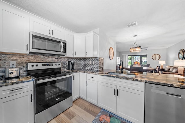 kitchen with decorative backsplash, appliances with stainless steel finishes, light wood-type flooring, sink, and white cabinets