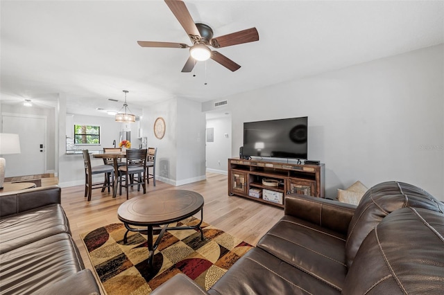 living room with light hardwood / wood-style flooring and ceiling fan with notable chandelier