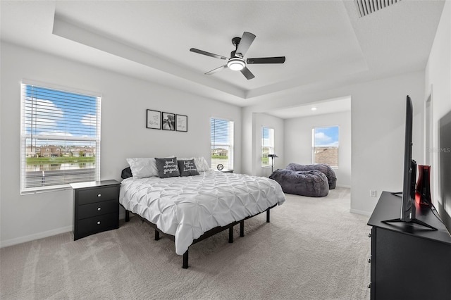 bedroom featuring ceiling fan, a raised ceiling, and carpet