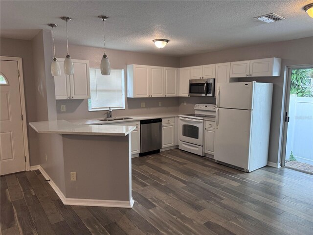 kitchen featuring white cabinets, kitchen peninsula, decorative light fixtures, appliances with stainless steel finishes, and dark hardwood / wood-style flooring