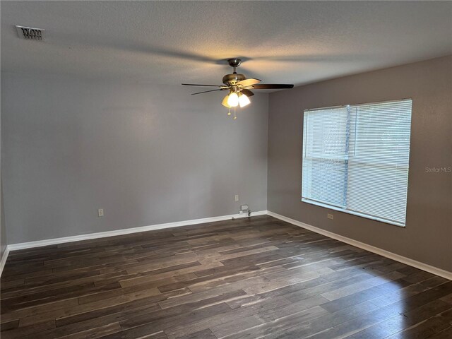 empty room featuring ceiling fan, dark hardwood / wood-style floors, and a textured ceiling