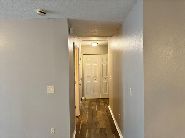 hallway featuring a textured ceiling and dark wood-type flooring