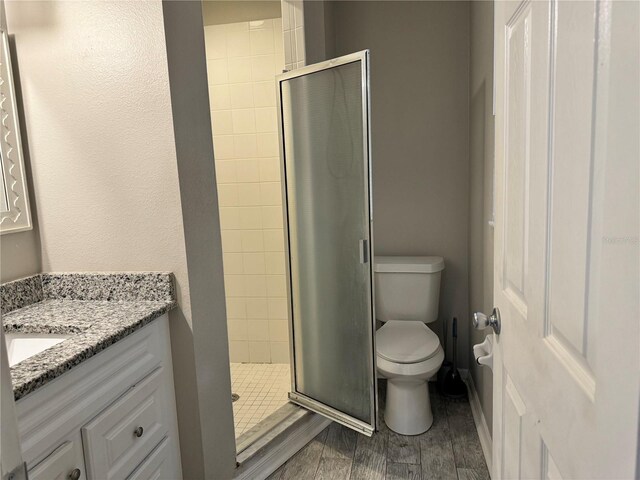 bathroom with vanity, hardwood / wood-style floors, a shower with shower door, and toilet