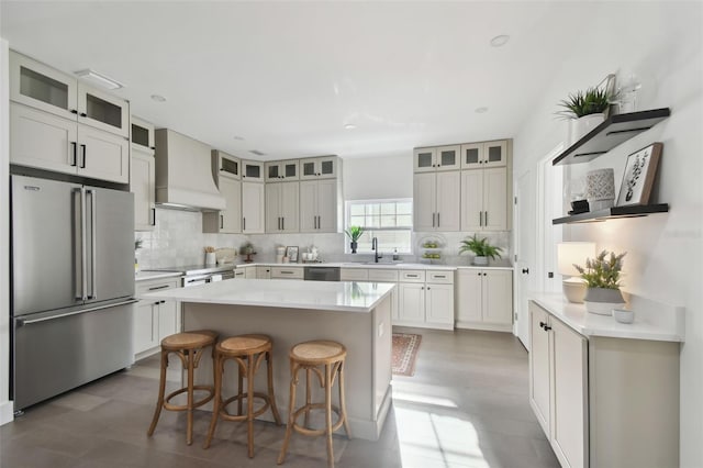 kitchen featuring white cabinetry, a kitchen island, stainless steel appliances, and custom exhaust hood