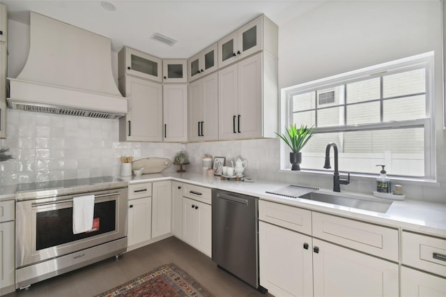 kitchen featuring custom exhaust hood, sink, appliances with stainless steel finishes, tasteful backsplash, and white cabinetry