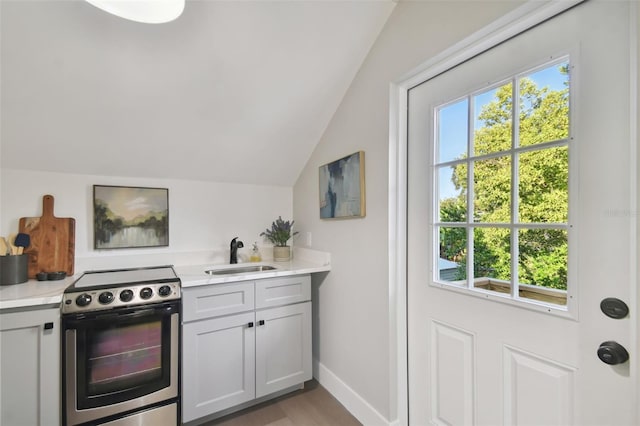 kitchen with sink, light hardwood / wood-style flooring, vaulted ceiling, stainless steel electric range, and white cabinets