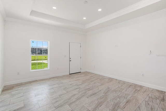 empty room featuring a tray ceiling and crown molding