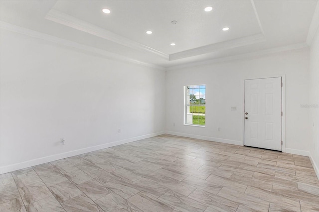 empty room with ornamental molding and a tray ceiling