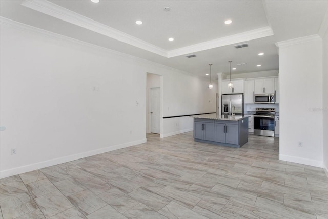 kitchen with white cabinets, a raised ceiling, ornamental molding, a center island with sink, and appliances with stainless steel finishes