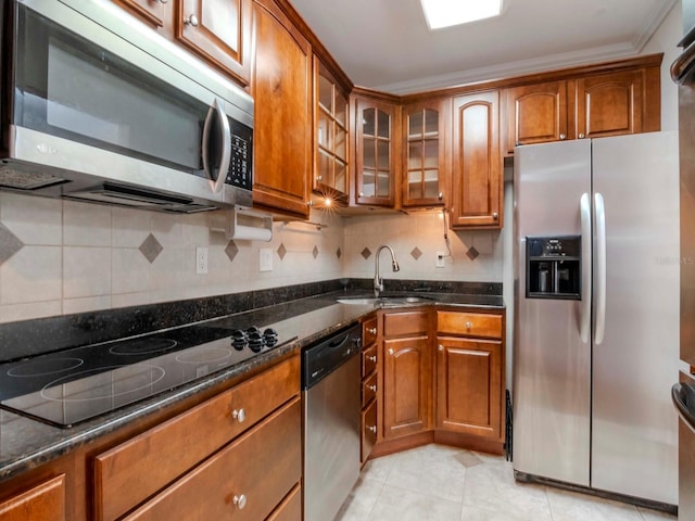 kitchen with sink, dark stone countertops, crown molding, light tile patterned floors, and appliances with stainless steel finishes