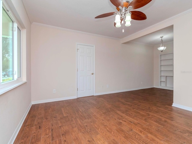 spare room featuring crown molding, built in features, and hardwood / wood-style flooring