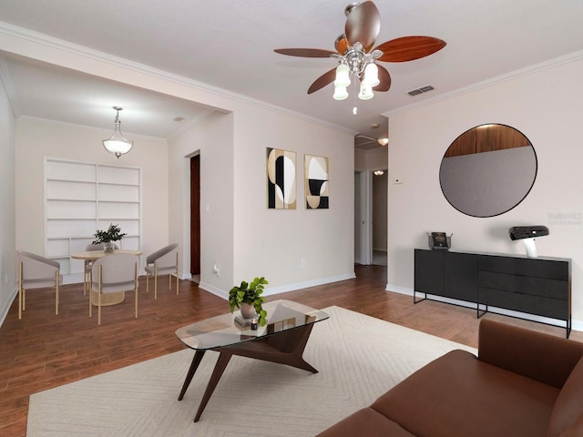 living room with built in shelves, dark hardwood / wood-style floors, ceiling fan, and crown molding