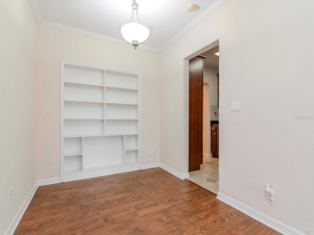 spare room with built in shelves, crown molding, and hardwood / wood-style flooring