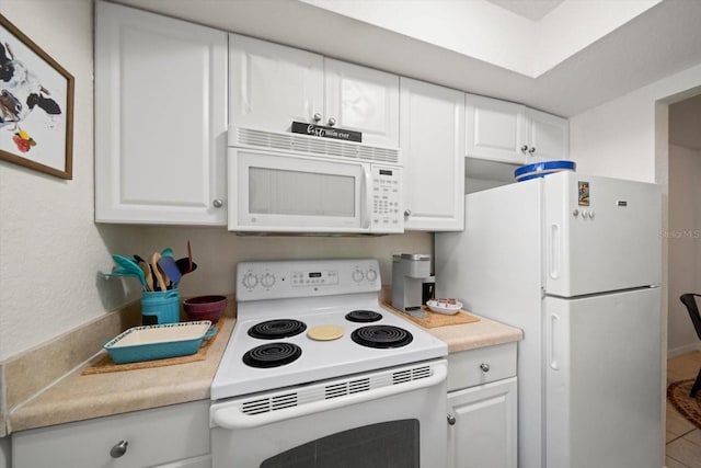 kitchen with white cabinets, white appliances, and tile patterned flooring