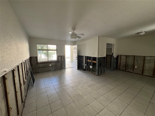 spare room featuring ceiling fan, light tile patterned flooring, and a textured ceiling