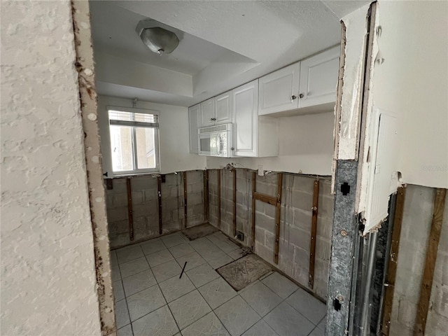 kitchen featuring white cabinets, light tile patterned floors, and tile walls