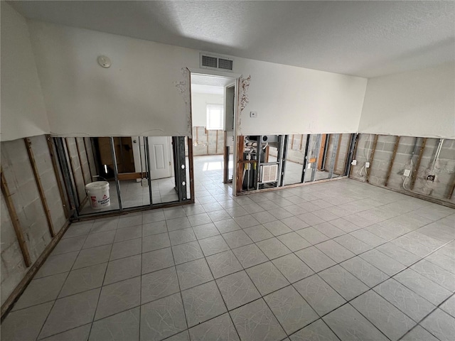 tiled empty room featuring a textured ceiling