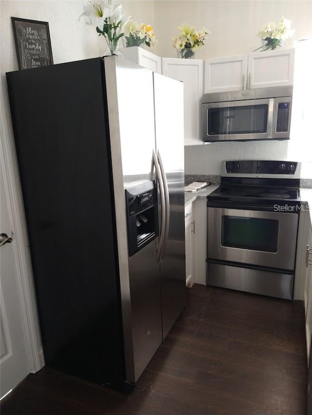 kitchen featuring appliances with stainless steel finishes, dark wood-type flooring, and white cabinets