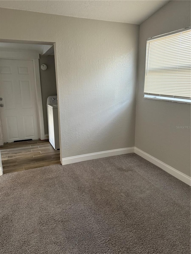 empty room featuring lofted ceiling, washer / clothes dryer, and hardwood / wood-style floors