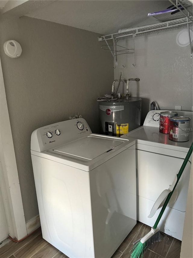 washroom with washing machine and clothes dryer, wood-type flooring, and water heater