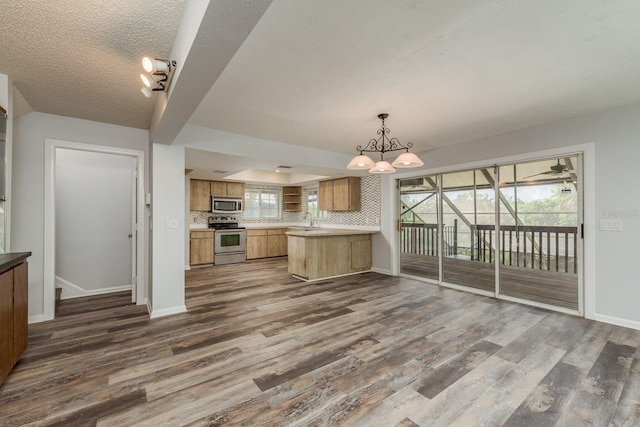 kitchen featuring appliances with stainless steel finishes, backsplash, kitchen peninsula, dark hardwood / wood-style flooring, and sink