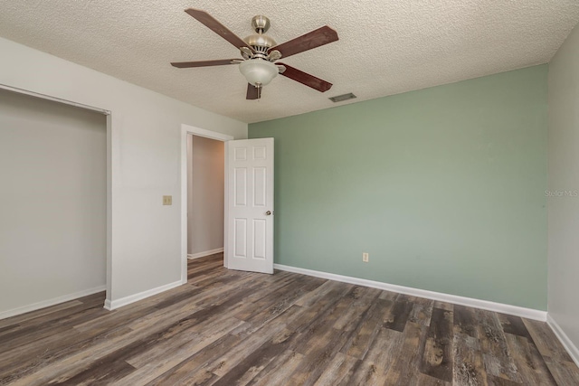 unfurnished bedroom with ceiling fan, a textured ceiling, a closet, and dark wood-type flooring