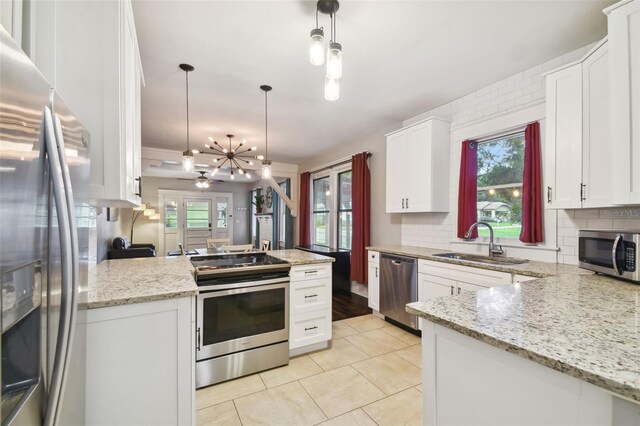 kitchen with stainless steel appliances, hanging light fixtures, sink, and a healthy amount of sunlight