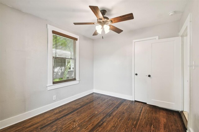 unfurnished bedroom with dark wood-type flooring, ceiling fan, and a closet