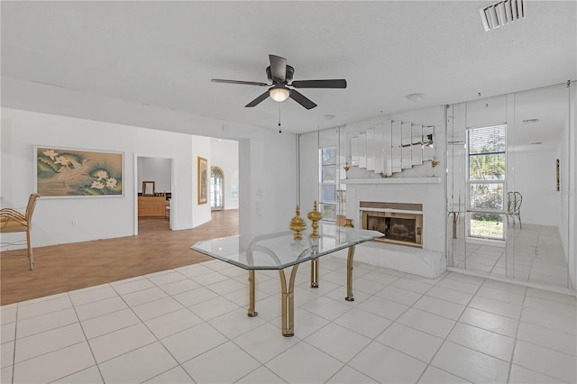 unfurnished living room featuring a fireplace, ceiling fan, light tile patterned floors, and a textured ceiling