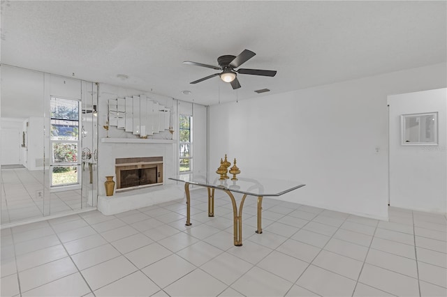 unfurnished living room featuring a textured ceiling, ceiling fan, and light tile patterned floors