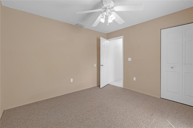 unfurnished bedroom featuring a textured ceiling, ceiling fan, a closet, and light colored carpet